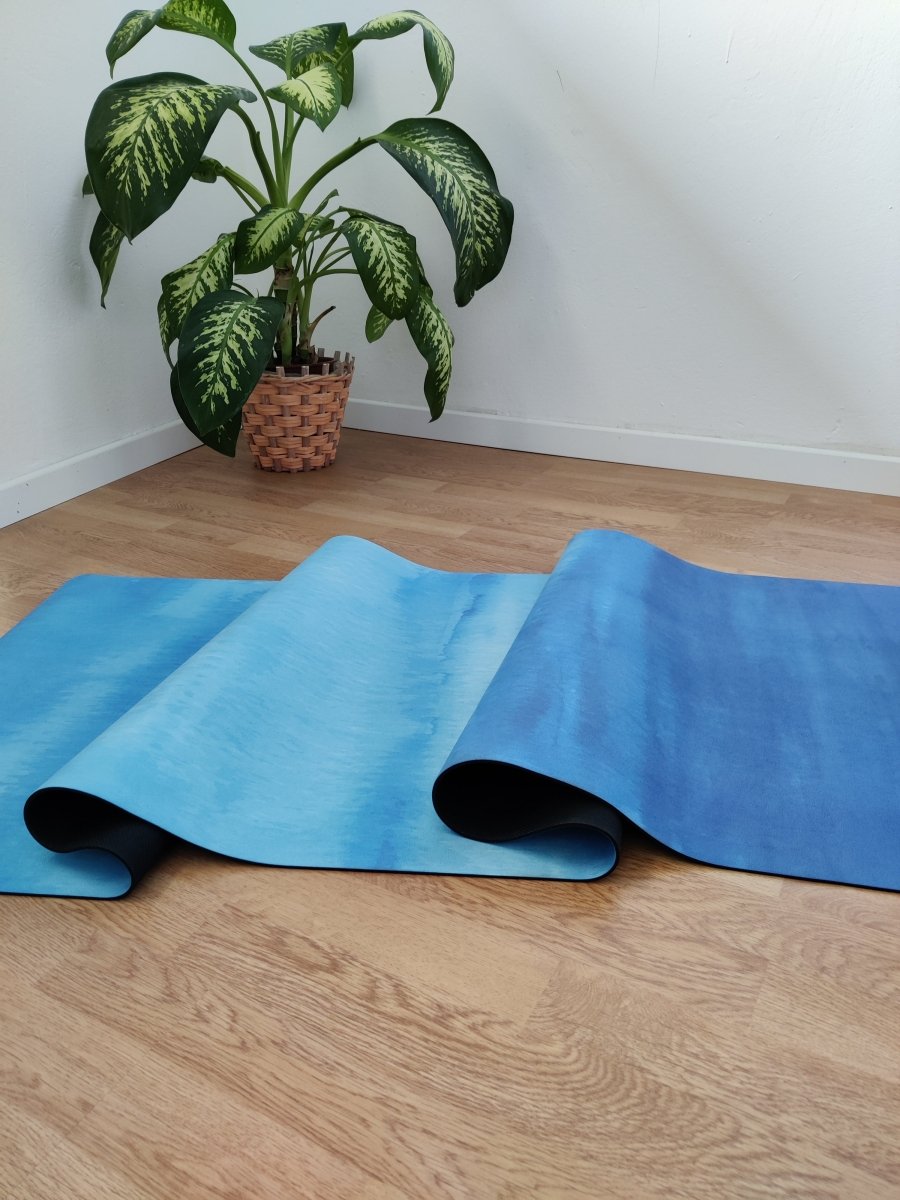 detail of blue yoga mat on wooden floor near indoor plant