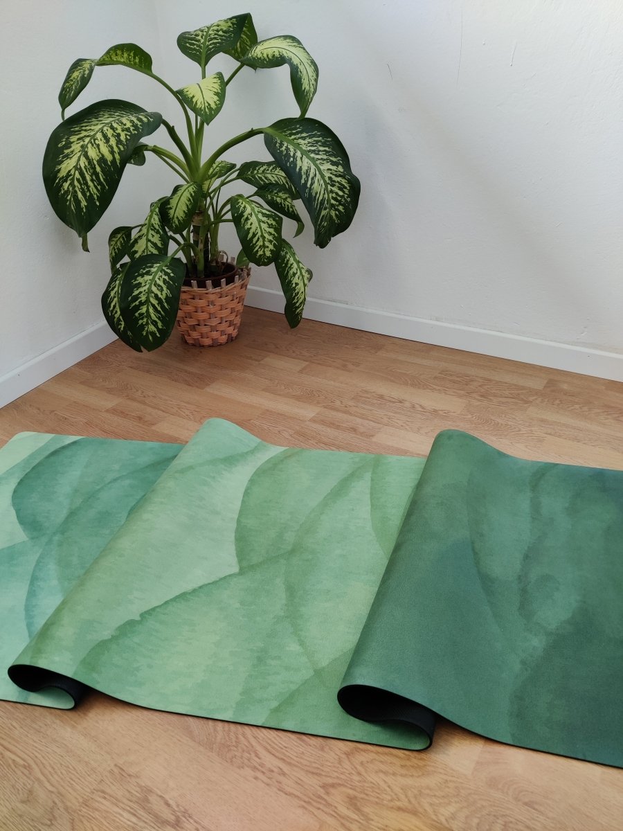 detail of green yoga mat on wooden floor near indoor plant