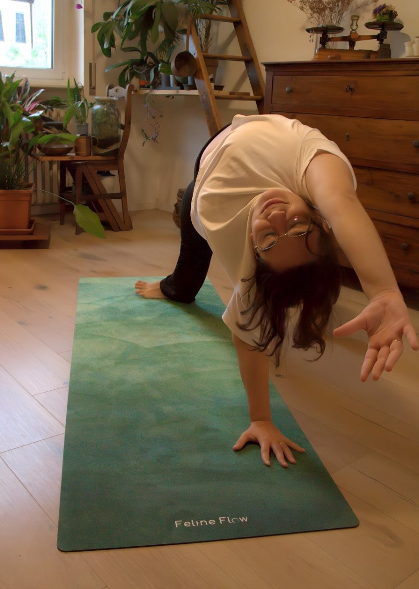 female stretching on green yoga mat in a living room with wooden floors