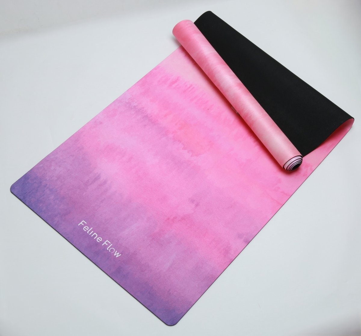 Fuchsia yoga mat half rolled on white background