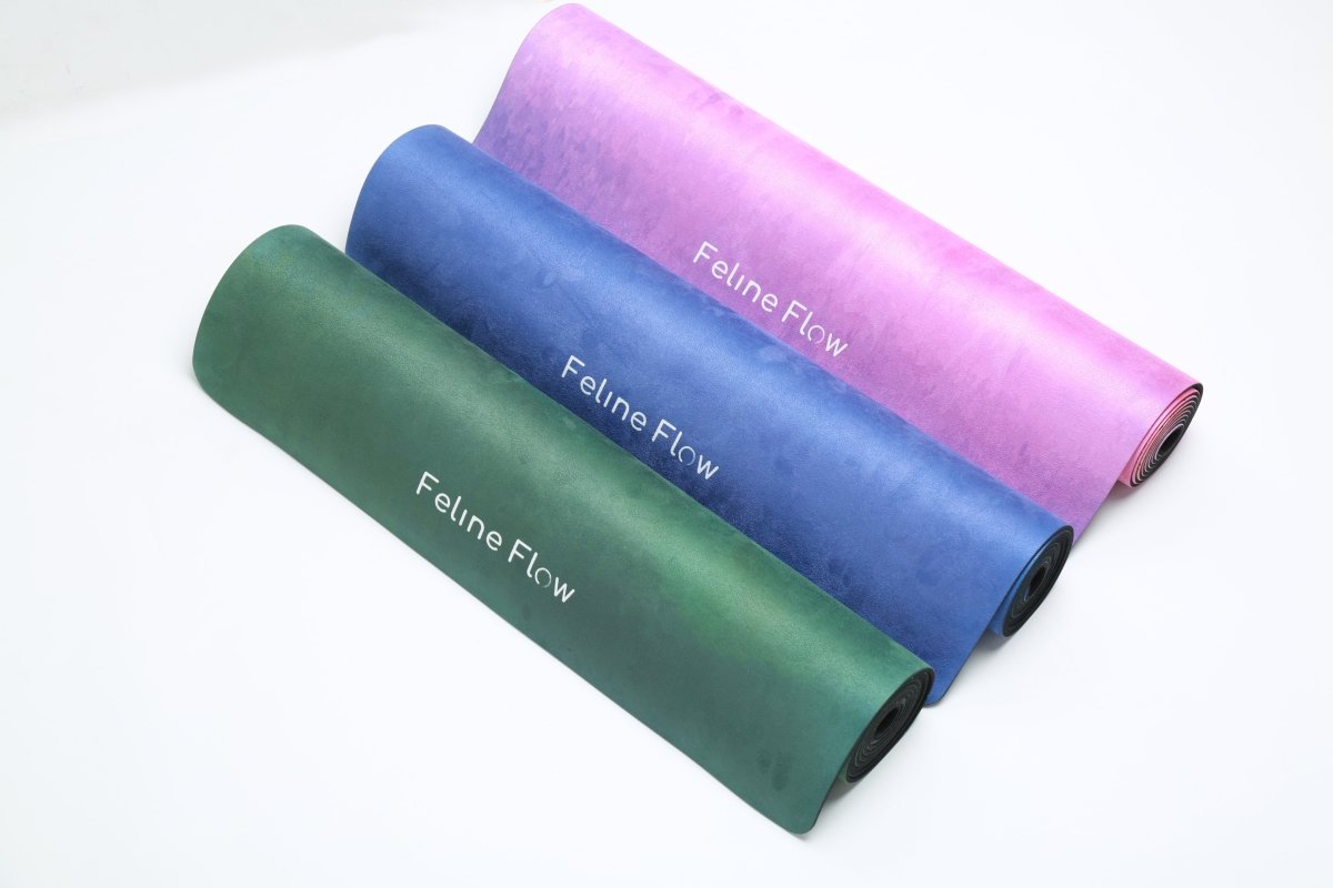 Rolled yoga mats green blue pink Feline Flow brand  from above white background
