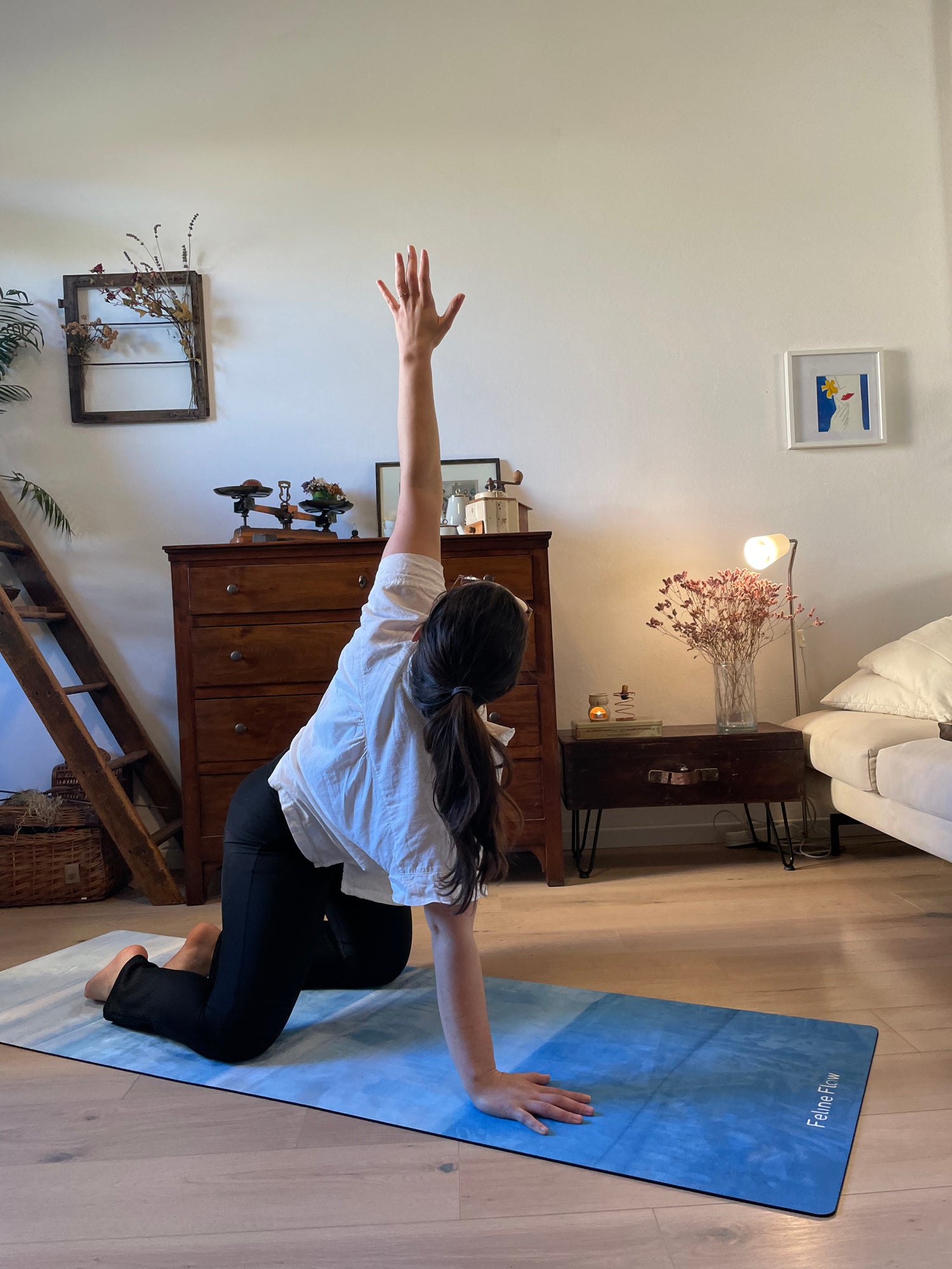 female stretching on blue yoga mat in living room wooden floors lamp sofa